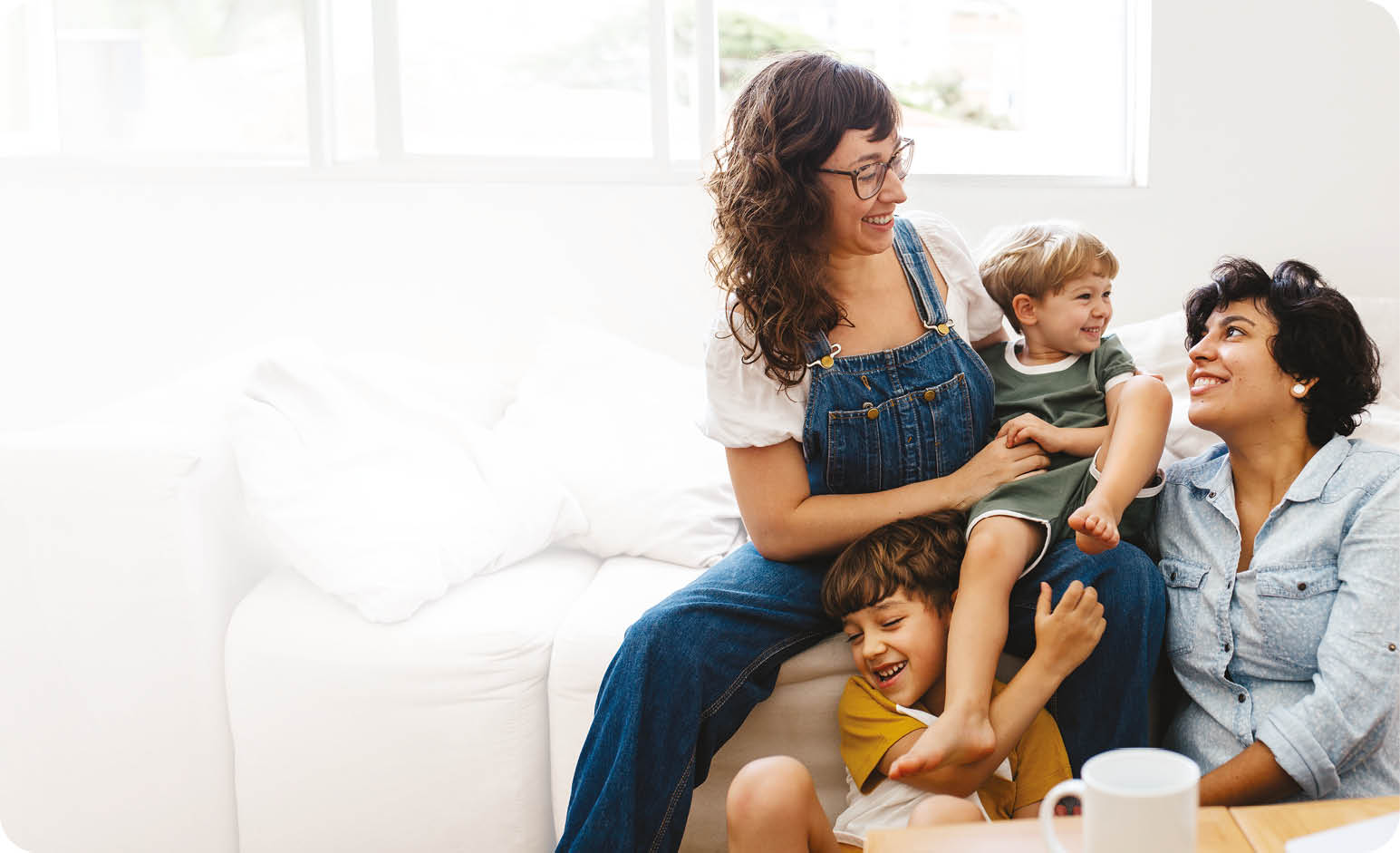 Happy lesbian couple playing with their children at home. Beautiful family of four having great time together indoors.