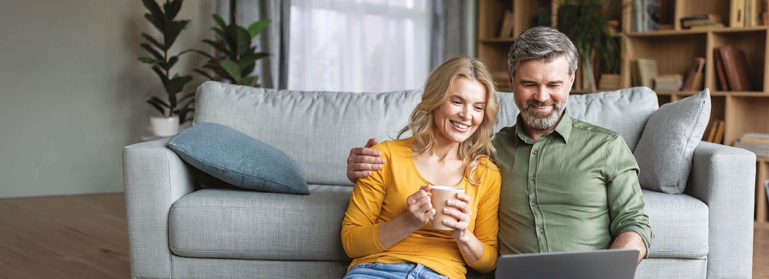 A man and woman sitting on a couch, both holding cell phones. Description generated by AI
