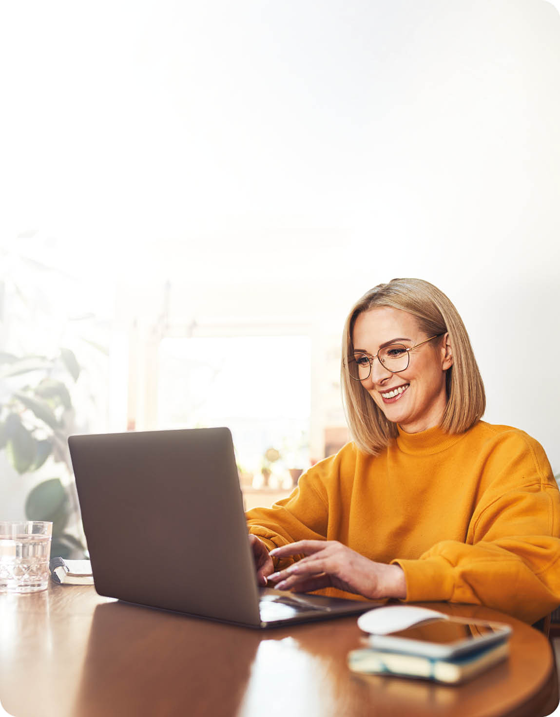 A woman is sitting at a desk using a laptop. Description generated by AI