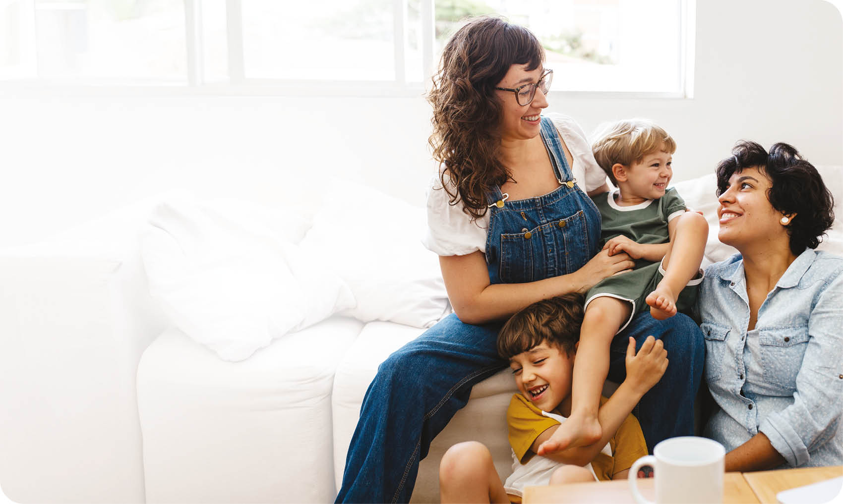 Happy lesbian couple playing with their children at home. Beautiful family of four having great time together indoors.
