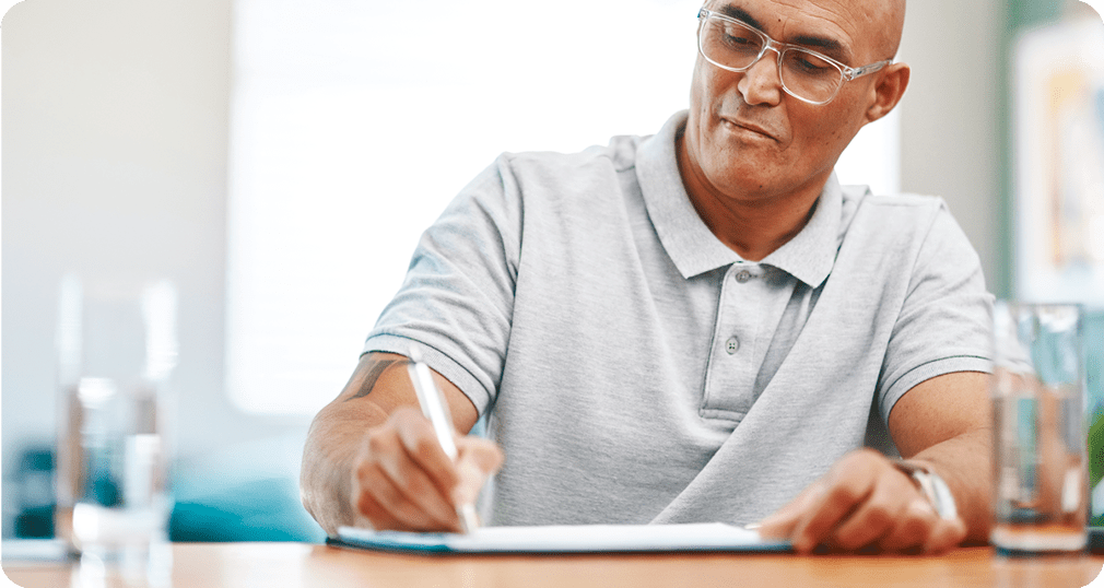 Home, documents and man writing, planning and life insurance with mortgage, update will and testament. Apartment, person or guy with paperwork, budget and retirement fund with schedule or information