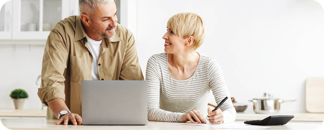 A man and woman are sitting at a kitchen counter. Description generated by AI