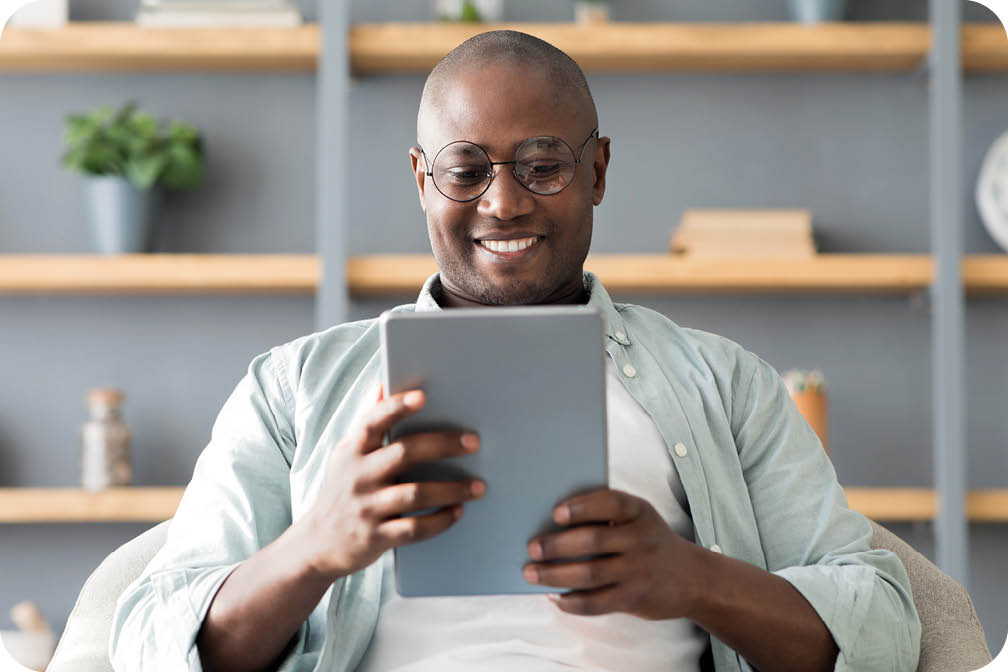 A man sitting in a chair holding a tablet. Description generated by AI