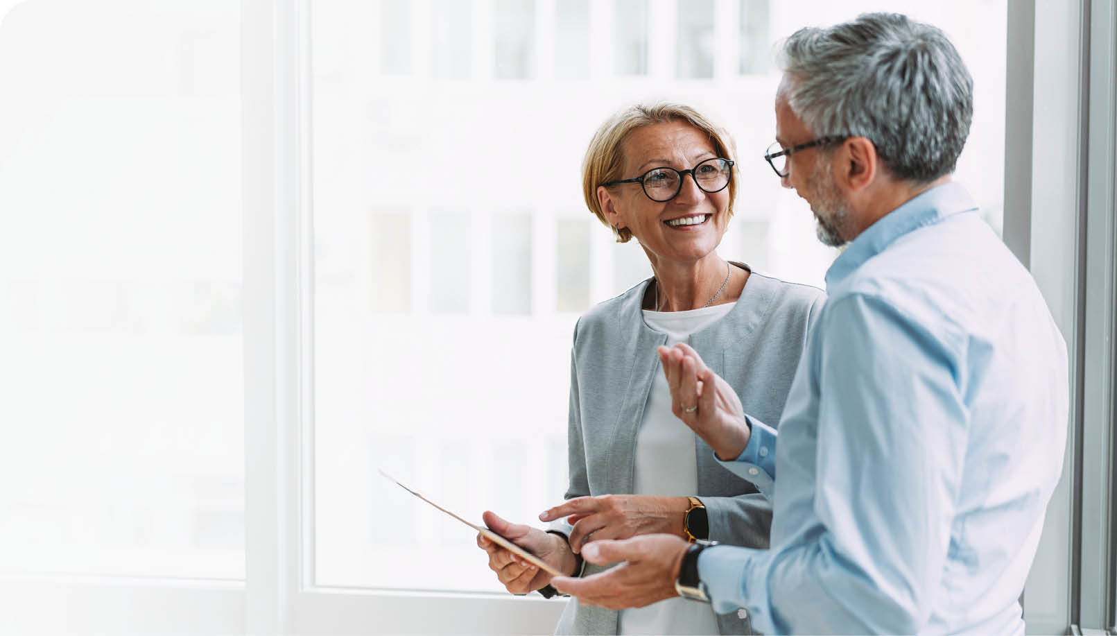 Shot of two coworkers having a discussion in modern office. Businessman and businesswoman in meeting using digital tablet and discussing business strategy. Confident business people working together in the office. Corporate business persons discussing new project and sharing ideas in the workplace.