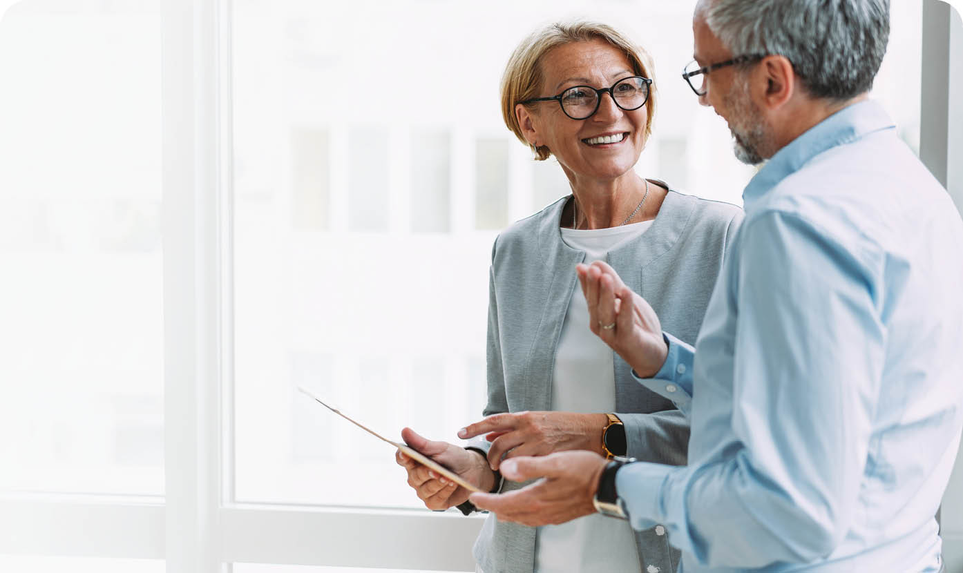 Shot of two coworkers having a discussion in modern office. Businessman and businesswoman in meeting using digital tablet and discussing business strategy. Confident business people working together in the office. Corporate business persons discussing new project and sharing ideas in the workplace.