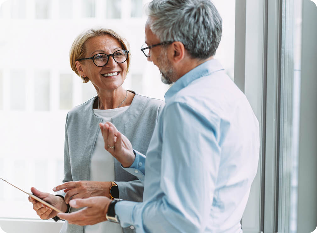 Shot of two coworkers having a discussion in modern office. Businessman and businesswoman in meeting using digital tablet and discussing business strategy. Confident business people working together in the office. Corporate business persons discussing new project and sharing ideas in the workplace.