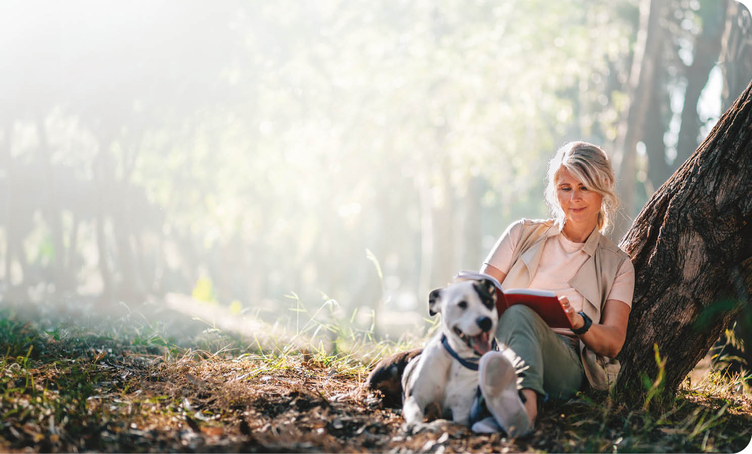 A woman is sitting on the ground next to a dog. She is reading a book. AI generated content