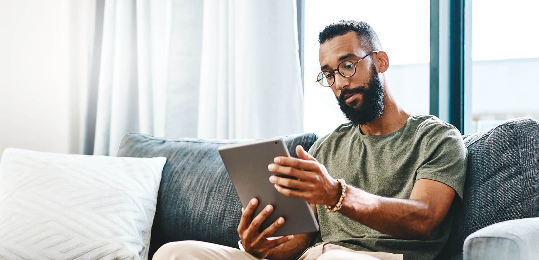Shot of a handsome young man using his digital tablet while sitting on a sofa at home