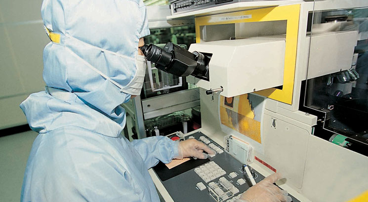 A technician in full protective clothing working in a lab