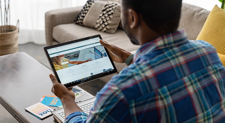 A man with his back to the camera looks at a tablet computer screen