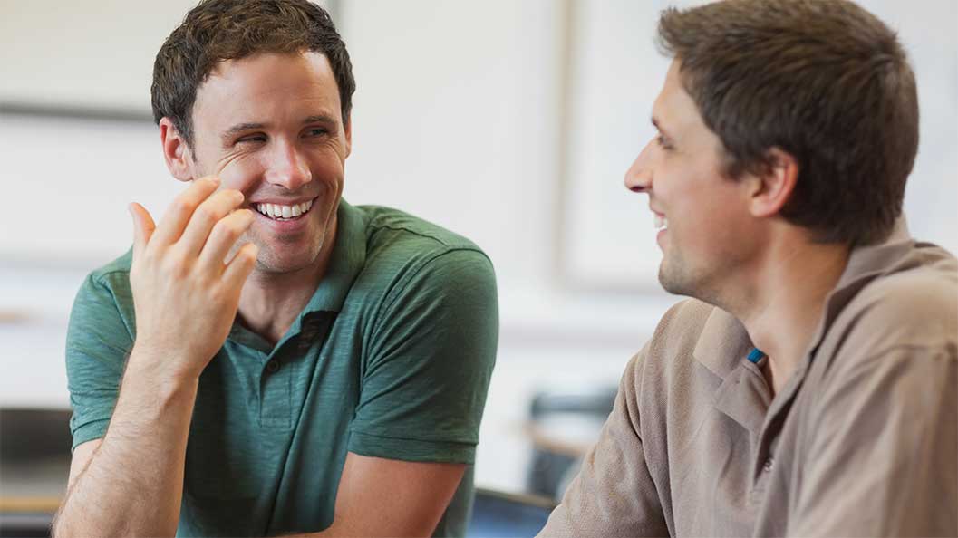 Two men smiling at each other while chatting