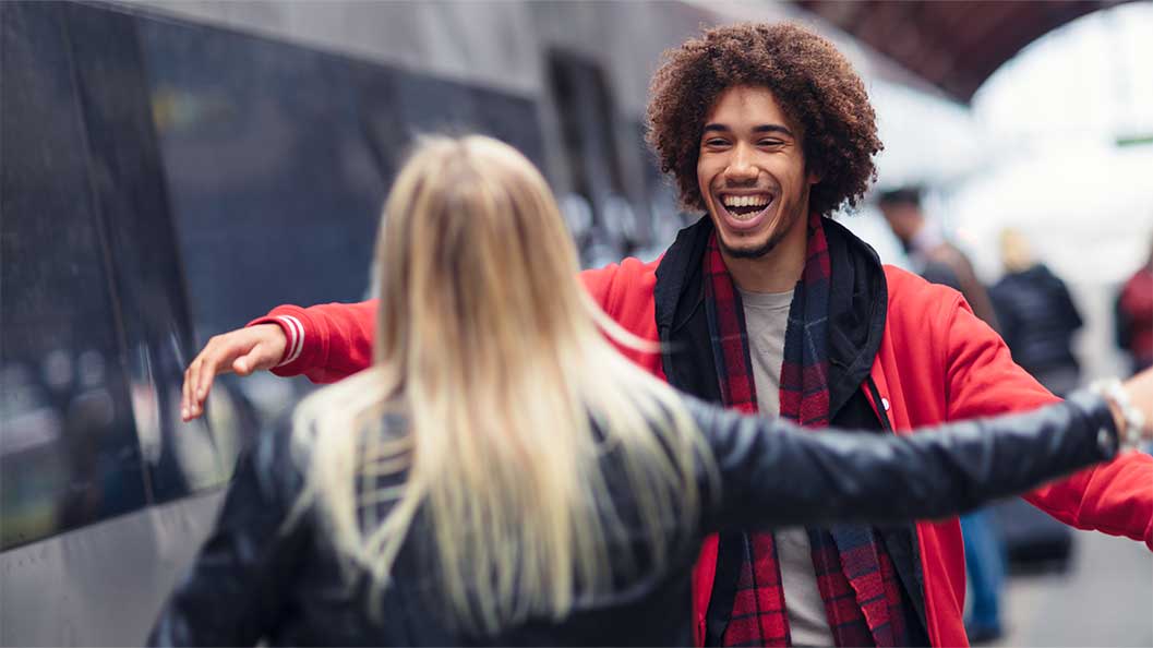 A man and a woman about to each other a hug at a train station
