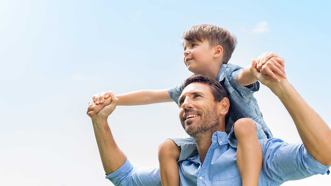 A boy on a man's shoulders both looking at the same direction