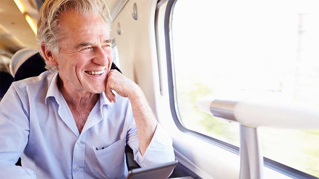 A man looking out a train window with a smile on his face